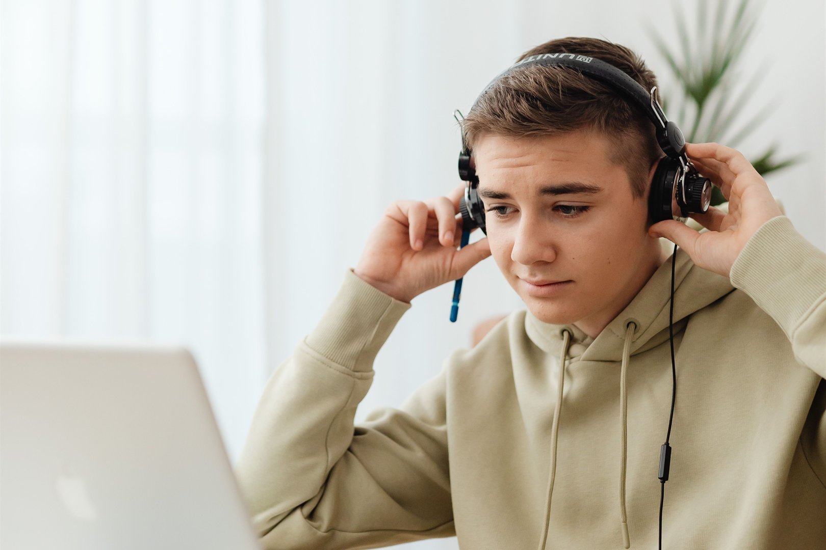 A teen in headphones working through the online driver education course on a laptop