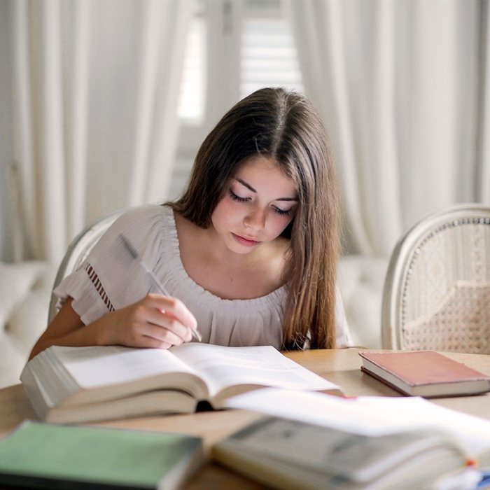 A teen studying from books for the DMV written permit test